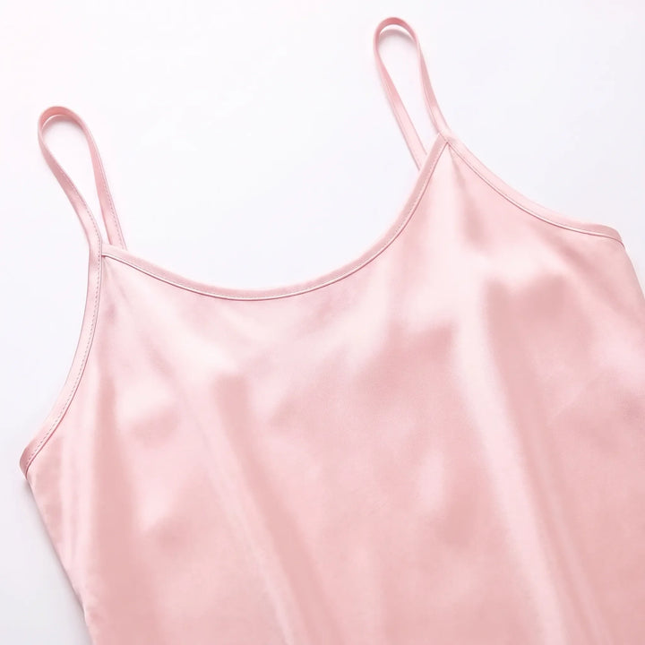 Flat lay close-up of the pale pink satin camisole's scoop neckline, thin straps and stitched edges. 5