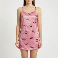 Front view of a model wearing a pink satin camisole nightgown printed with black hearts and closed-eye lash motifs. 10