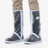 Clear transparent shoe covers with white trim and zipper worn over black lace-up boots, shown front view on a white background. 2