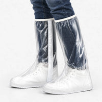 Side angle of clear tall overshoes with white trim and a vertical white strip, worn over white sneakers and jeans on a light background. 5