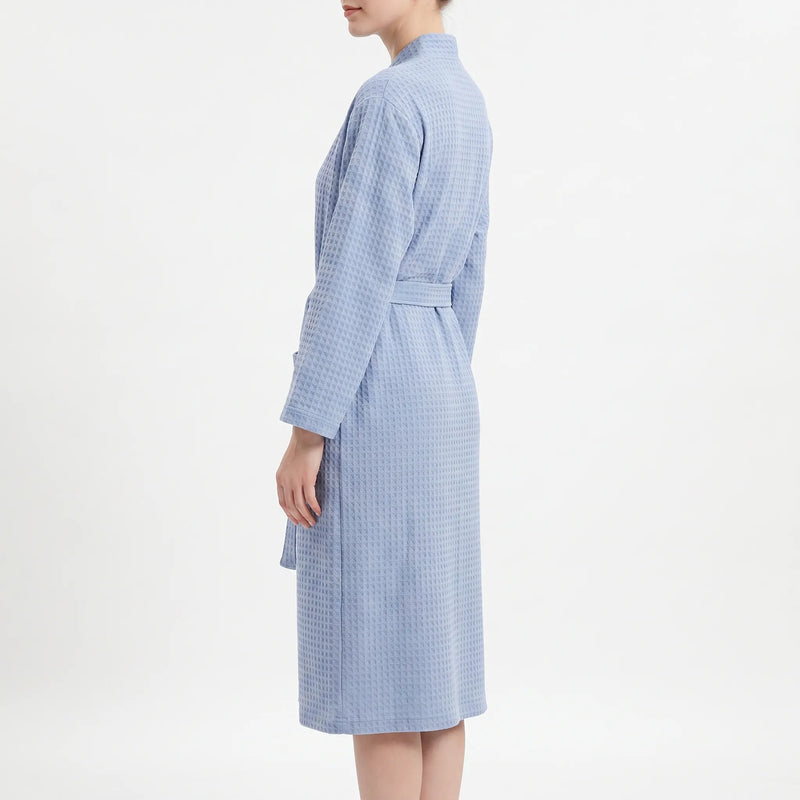 Side view of the blue waffle robe on a model, showing the long sleeve, belt and knee-length hem. 4