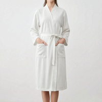 Model wearing the robe in white, hands in the patch pockets, belt tied in a bow at the waist. 7