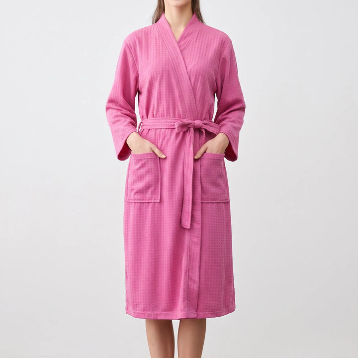 Model wearing the robe in bright pink, hands in the patch pockets, belt tied in a bow at the waist. 9
