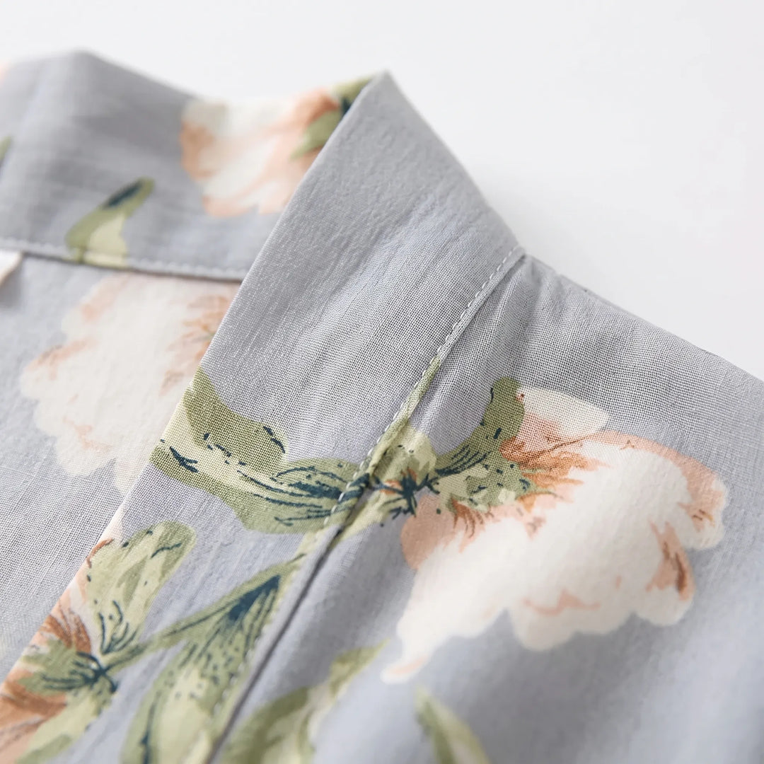 Close-up of the grey fabric's collar edge with stitching and a printed peach and white flower with green leaves. 5