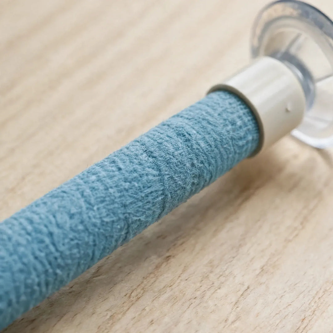 Close-up of the blue textured wrap on the perch, its white end cap and clear suction cup resting on a light wooden surface. 4