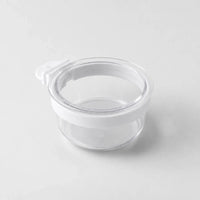 Empty clear plastic bowl with a white rim band and a small white hook tab on one side, shown on a plain grey background. 1