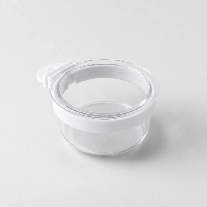 Empty clear plastic bowl with a white rim band and a small white hook tab on one side, shown on a plain grey background. 1