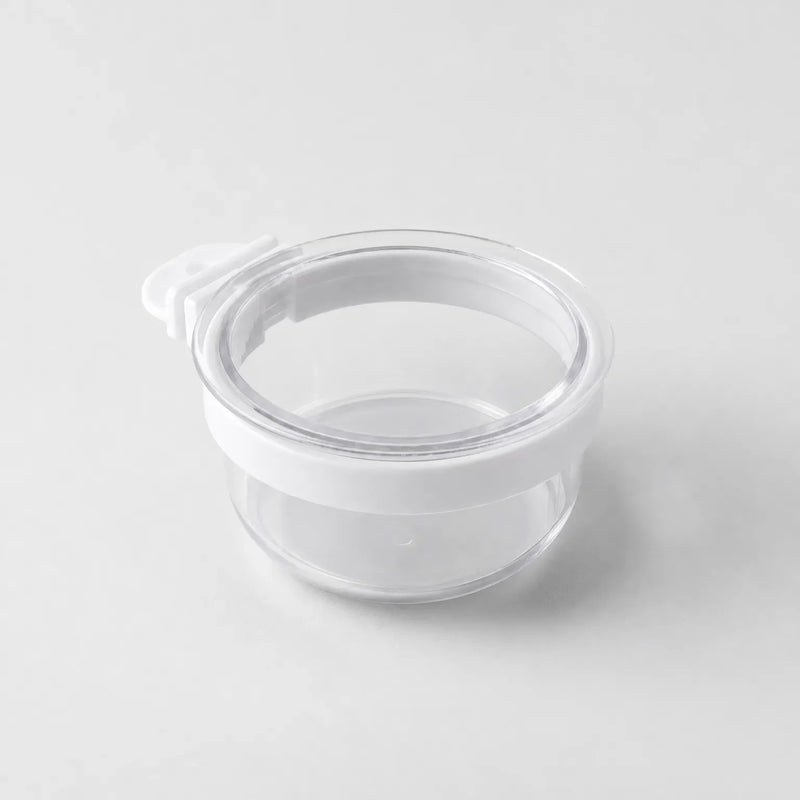 Empty clear plastic bowl with a white rim band and a small white hook tab on one side, shown on a plain grey background. 1