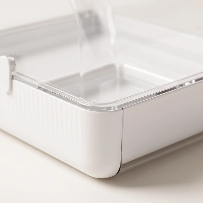 Close-up of the white ribbed base, clear rim and small latch, with the water tray visible inside. 3