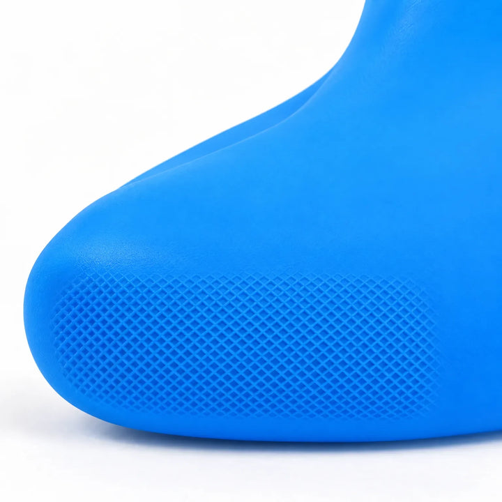 Close-up of the toe of a blue rubber shoe cover, showing the fine diamond-pattern grip texture against a white background. 6