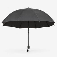 Open dark grey umbrella seen from the side on white, showing its wide canopy, black lining and handle with wrist loop. 3