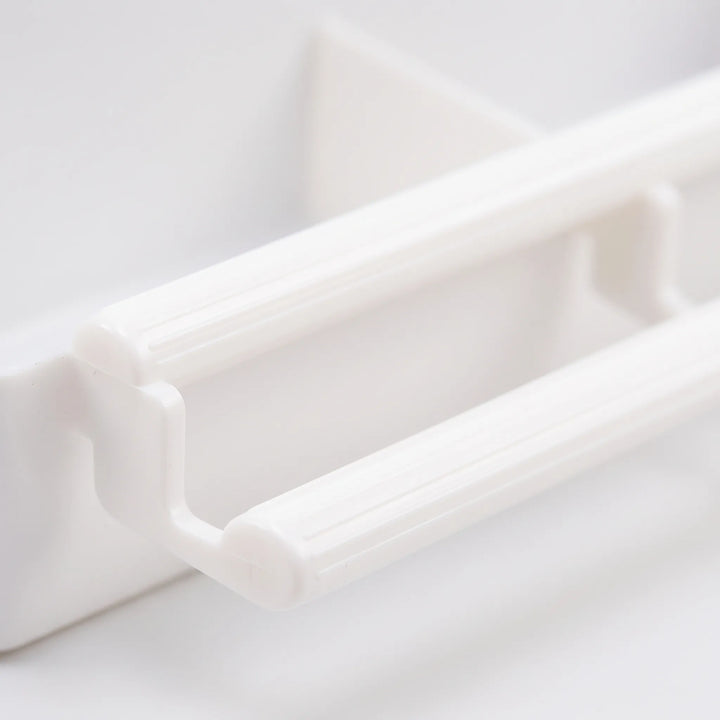 Close-up of the feeder's two ribbed white plastic perch bars and their connecting bracket on the front of the tray. 3
