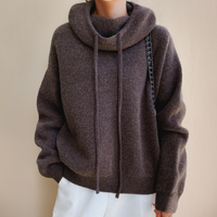 Front view of a brown roll neck jumper with two drawstrings, worn with white trousers 8
