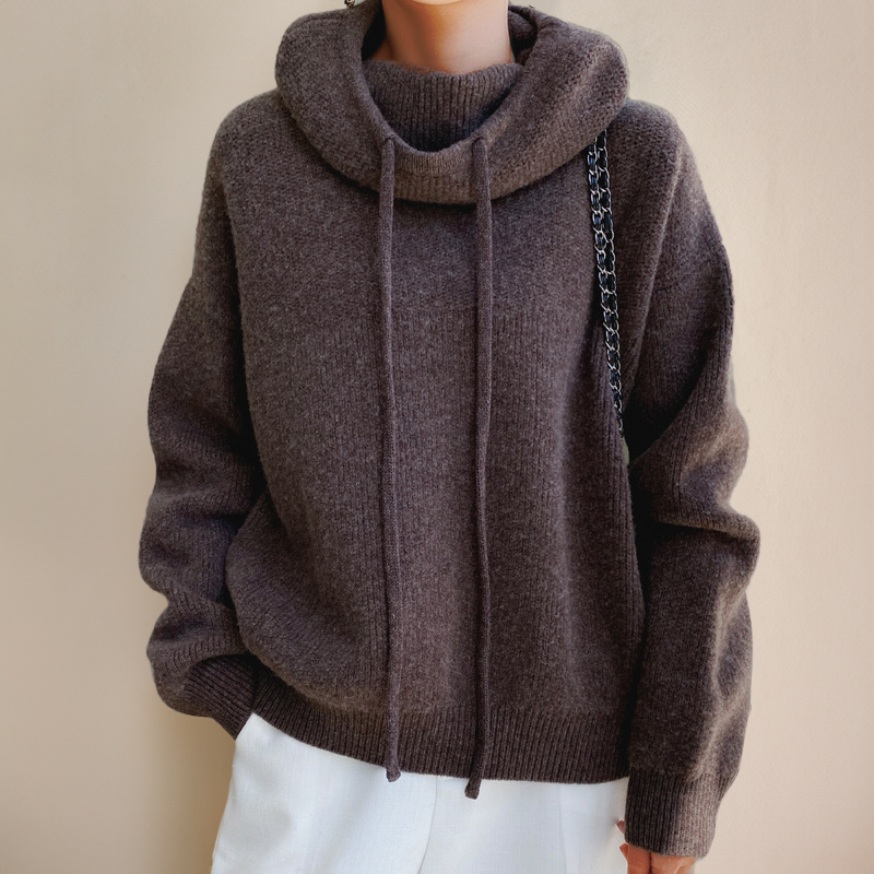 Front view of a brown ribbed jumper with drawstring roll neck, long sleeves and white trousers 7