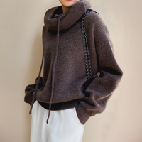 Brown jumper with relaxed sleeves and drawstring cowl neck, worn with white trousers and a chain bag 7