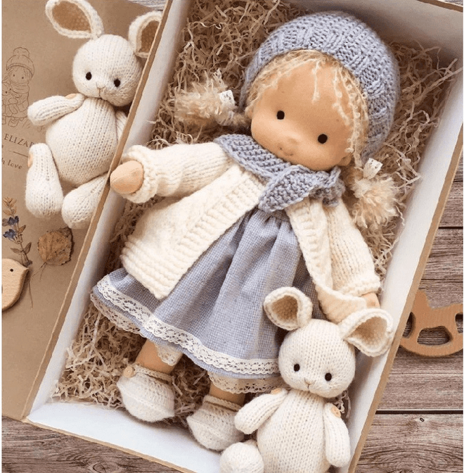 Doll in grey knitted bonnet, cream cardigan and lace-trimmed dress, boxed with two knitted bunnies 4