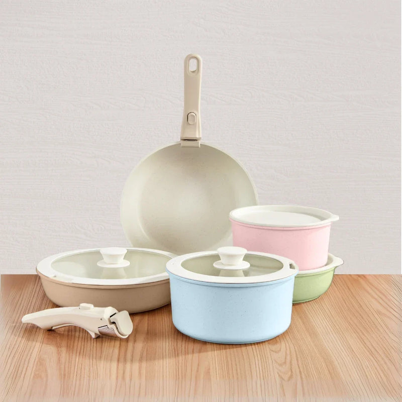 Pastel pink, blue, green and beige pans with glass lids, a cream frying pan and a detachable handle on a wooden surface 1