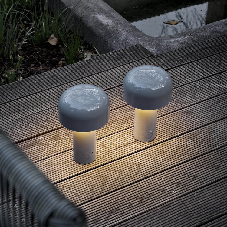 Two grey mushroom lamps lit on a wooden garden deck beside a woven chair 22