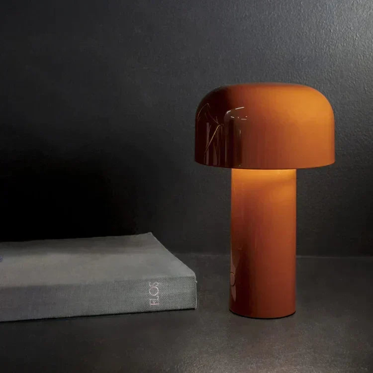 Orange glossy mushroom lamp glowing in a dark setting next to a grey hardback book 8