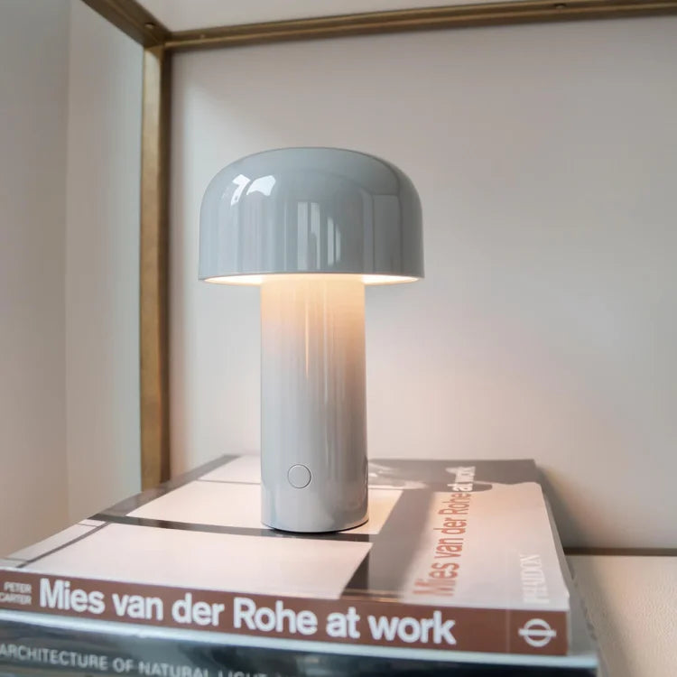 Light grey mushroom lamp glowing on top of a stack of architecture books 10