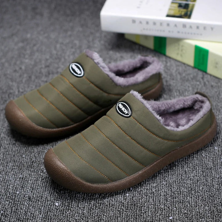 Olive green quilted slippers with grey fleece lining on a grey carpet beside books 2