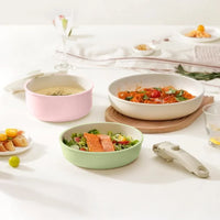 Pastel pink, green and cream pans holding soup, pasta and salmon salad on a set table, detachable handle beside them 2